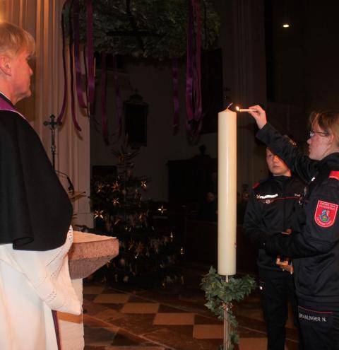 Ein Mädchen der Jugendfeuerwehr Ostermiething entzündet die Kerze mit dem Friedenslicht aus Bethlehem